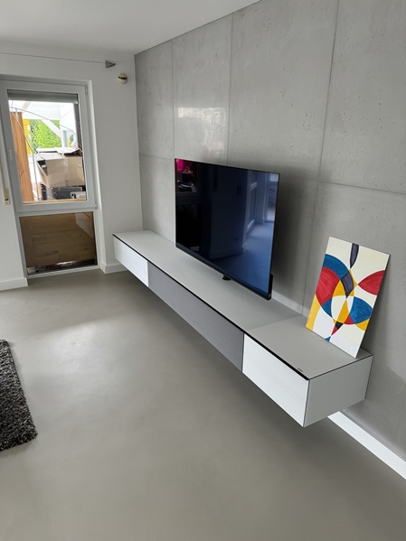 Wohnzimmer mit fugenlosem Bodenbelag und Sichtbeton an den Wänden