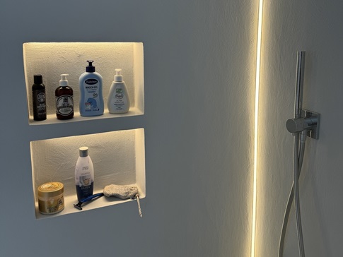 Beleuchtete Ablagenische in einem fugenlosem Bad